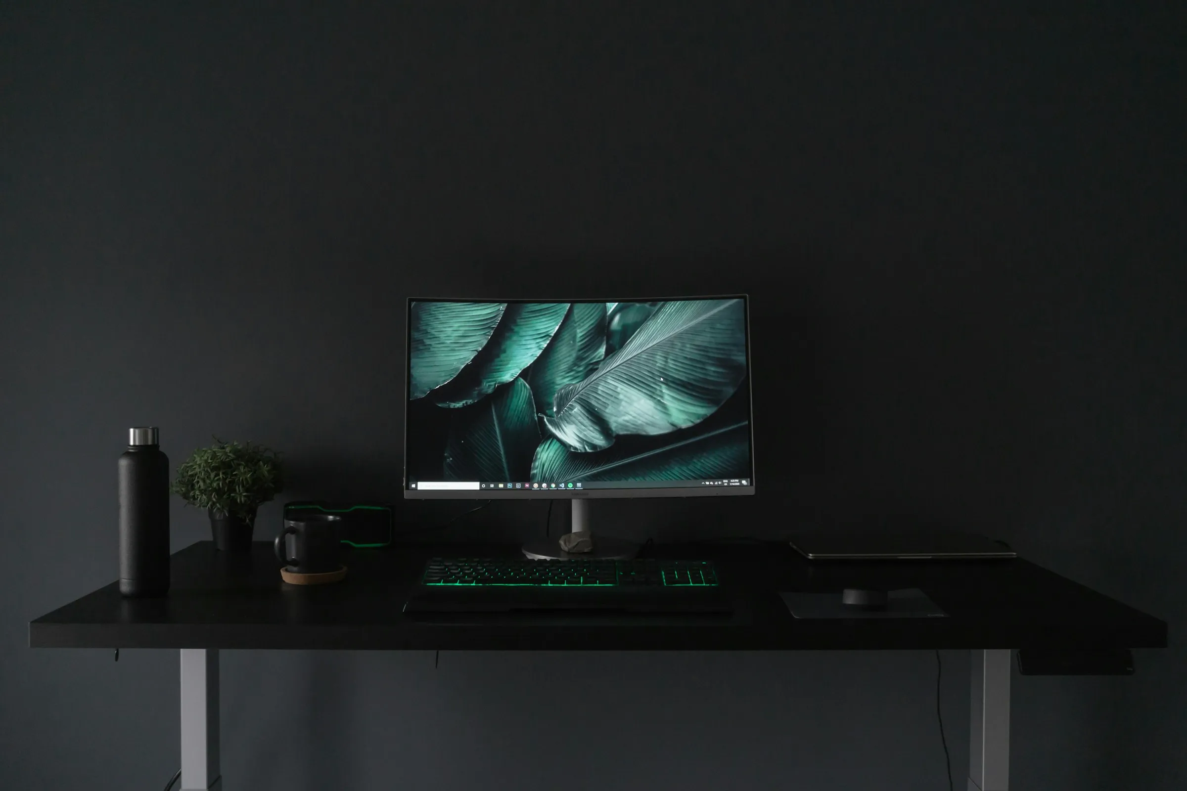 Escritorio minimalista negro con un monitor en una habitación oscura